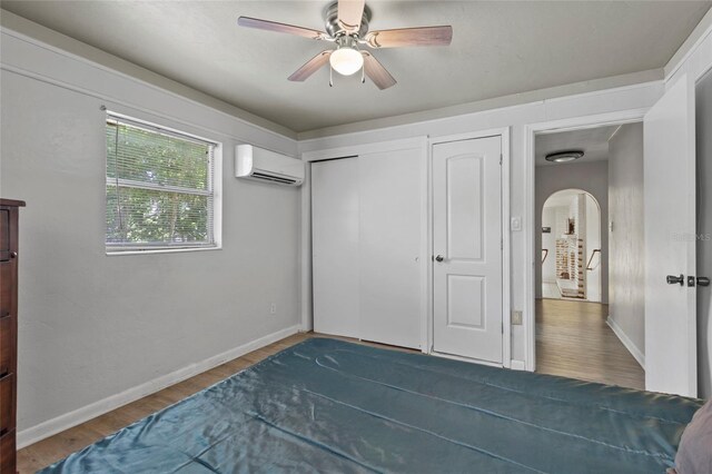 3058 SE 3rd Ave, Ocala, FL 34471 - bedroom featuring arched walkways, a wall mounted AC, baseboards, and wood finished floors