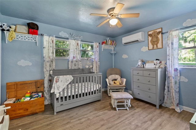 3058 SE 3rd Ave, Ocala, FL 34471 - bedroom with a crib, baseboards, ceiling fan, wood finished floors, and a wall mounted AC