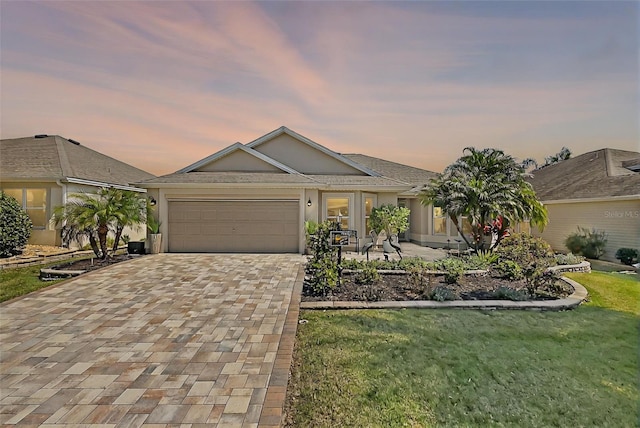 view of front of house with stucco siding, an attached garage, decorative driveway, and a front yard