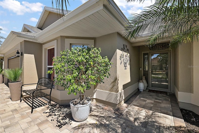 doorway to property with stucco siding and a garage