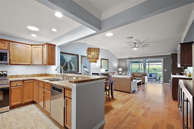 kitchen with open floor plan, vaulted ceiling, appliances with stainless steel finishes, a peninsula, and a sink