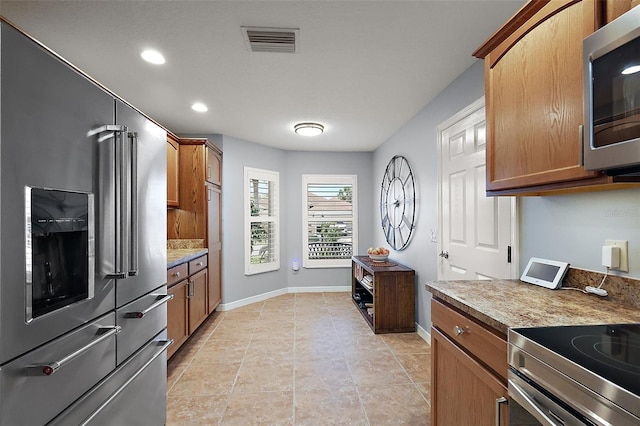 kitchen with visible vents, brown cabinets, appliances with stainless steel finishes, and baseboards