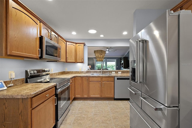 kitchen with brown cabinets, a sink, recessed lighting, appliances with stainless steel finishes, and ceiling fan