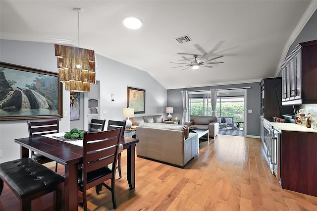 dining area with light wood-style flooring, crown molding, and vaulted ceiling