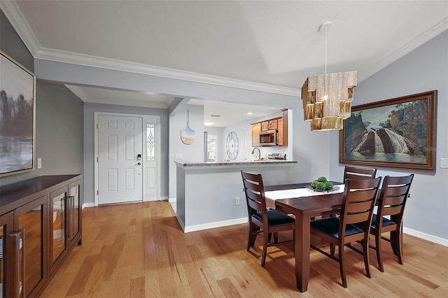 dining area with a notable chandelier, baseboards, crown molding, and light wood-style floors