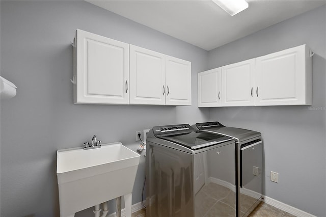 clothes washing area with a sink, baseboards, cabinet space, and independent washer and dryer