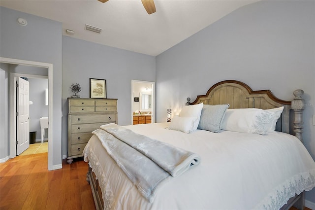 bedroom featuring visible vents, ensuite bathroom, wood finished floors, baseboards, and ceiling fan