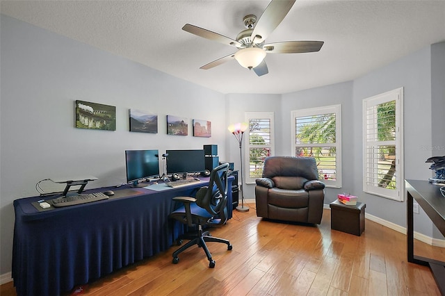 home office featuring a ceiling fan, baseboards, wood-type flooring, and a textured ceiling