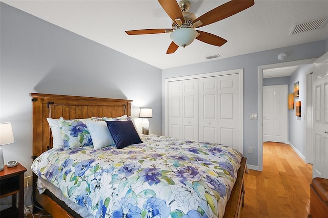 bedroom with light wood finished floors, visible vents, ceiling fan, and a closet