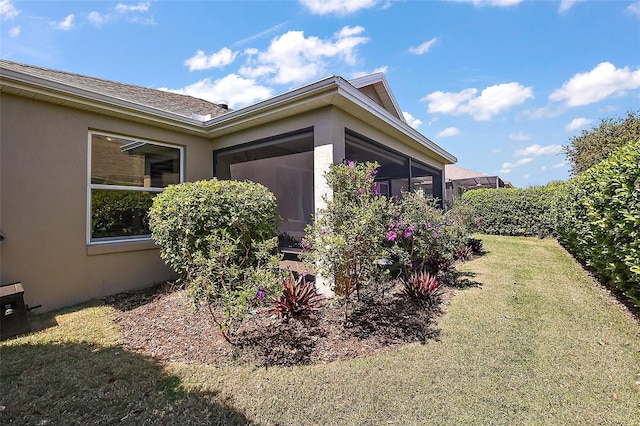 view of side of property featuring a yard, a sunroom, and stucco siding