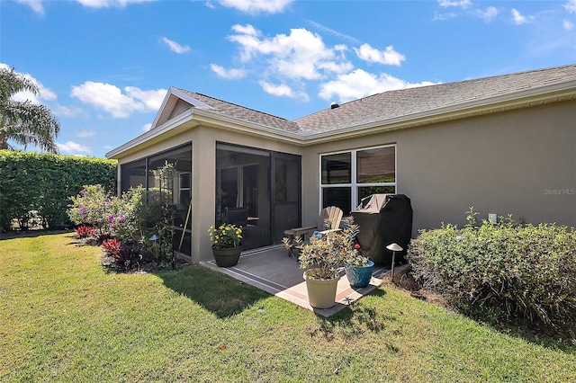 rear view of property with stucco siding, a shingled roof, a yard, and a sunroom