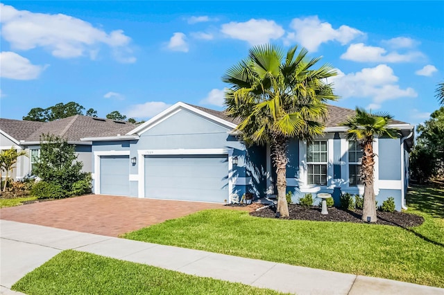 ranch-style home featuring stucco siding, an attached garage, decorative driveway, and a front yard