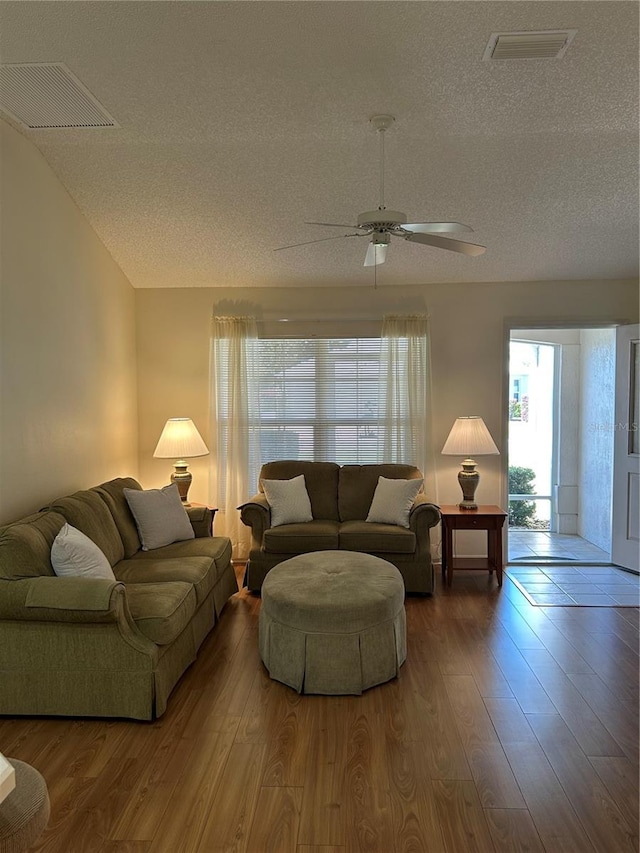 living room featuring visible vents, a textured ceiling, and wood finished floors