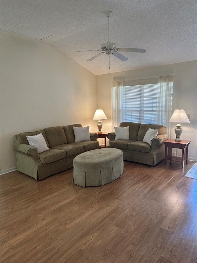 living area featuring lofted ceiling, a ceiling fan, a textured ceiling, wood finished floors, and baseboards