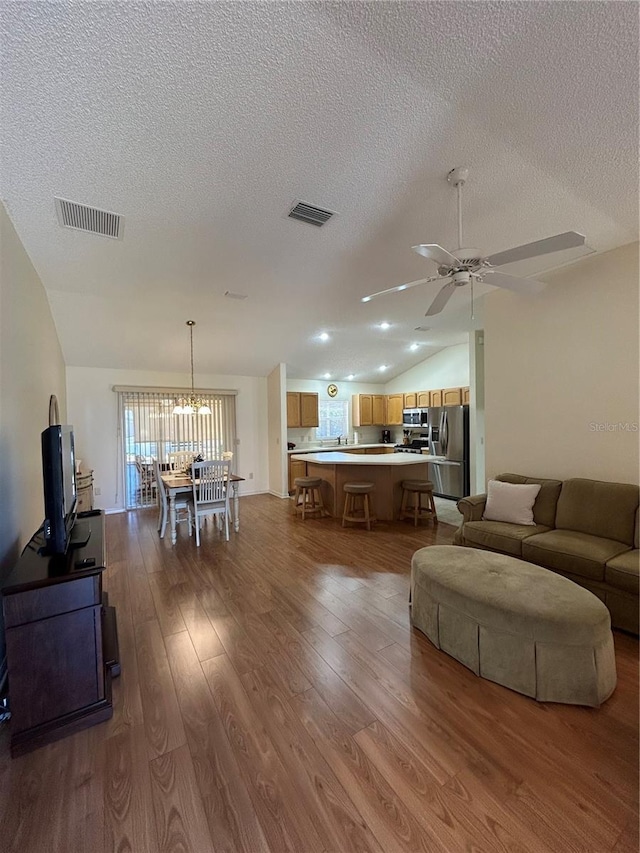 living area featuring visible vents, dark wood finished floors, a ceiling fan, and vaulted ceiling