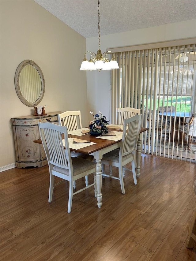 dining area with a notable chandelier, lofted ceiling, a textured ceiling, and wood finished floors