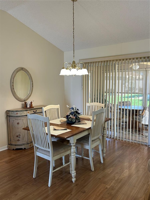 dining area featuring a notable chandelier, a textured ceiling, lofted ceiling, and wood finished floors