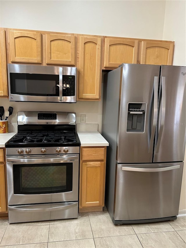 kitchen with light countertops, light tile patterned flooring, and appliances with stainless steel finishes