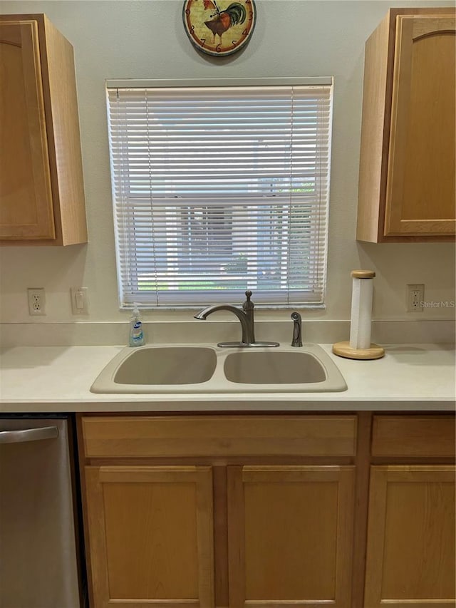 kitchen with stainless steel dishwasher, light countertops, and a sink