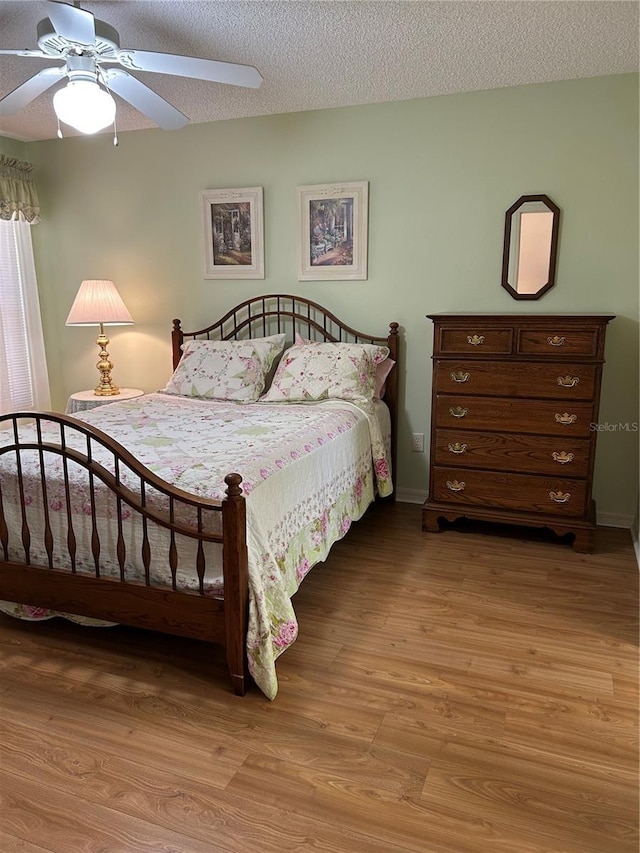 bedroom featuring light wood finished floors, a textured ceiling, and a ceiling fan