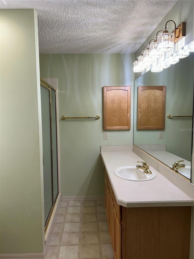 bathroom featuring a stall shower, vanity, and a textured ceiling