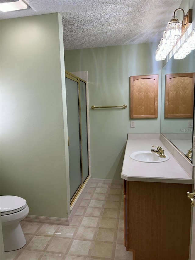 bathroom featuring a shower stall, baseboards, toilet, vanity, and a textured ceiling