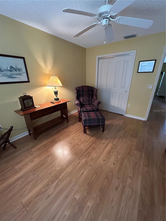 sitting room featuring baseboards, wood finished floors, visible vents, and a textured ceiling