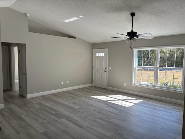 interior space with baseboards, lofted ceiling, a textured ceiling, and wood finished floors