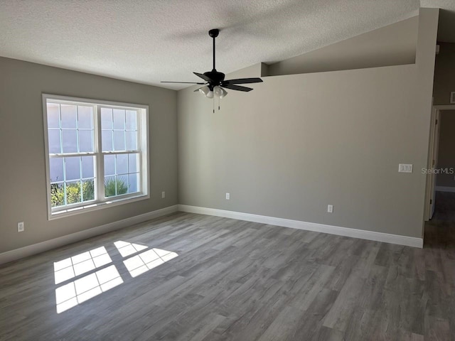 spare room with ceiling fan, baseboards, lofted ceiling, wood finished floors, and a textured ceiling