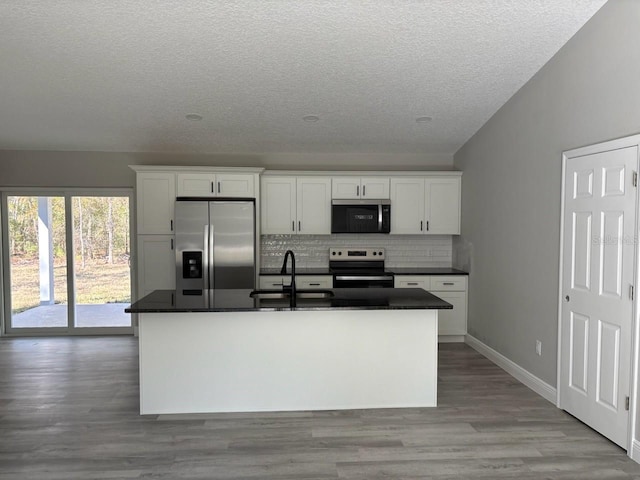 kitchen with a sink, dark countertops, backsplash, white cabinetry, and stainless steel appliances