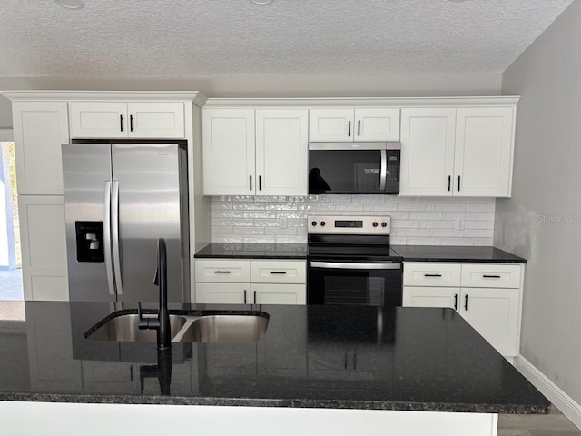 kitchen with a sink, stainless steel appliances, backsplash, and white cabinetry