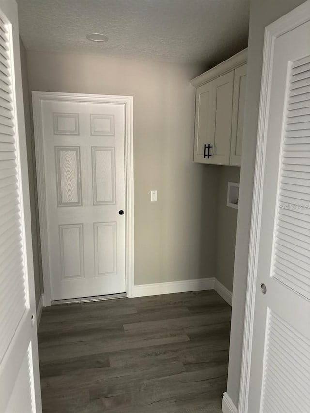 clothes washing area featuring dark wood-type flooring, a textured ceiling, baseboards, hookup for a washing machine, and laundry area