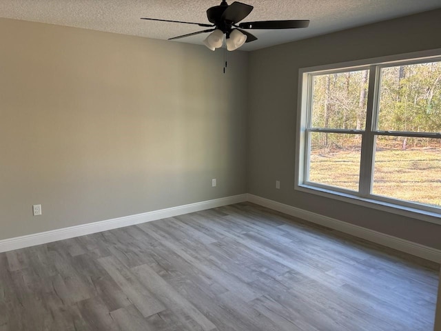 spare room with ceiling fan, a textured ceiling, baseboards, and wood finished floors