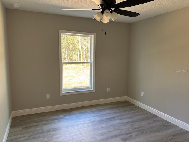 empty room with baseboards, a textured ceiling, and wood finished floors