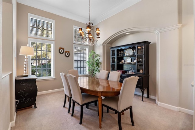 dining space featuring an inviting chandelier, crown molding, baseboards, and light carpet