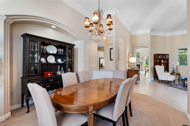 dining area featuring crown molding, light tile patterned floors, light carpet, an inviting chandelier, and arched walkways