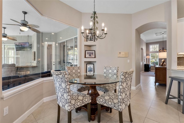 dining area featuring arched walkways, light tile patterned floors, ceiling fan with notable chandelier, and baseboards