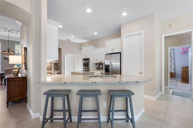 kitchen featuring a sink, tasteful backsplash, appliances with stainless steel finishes, white cabinets, and light stone countertops