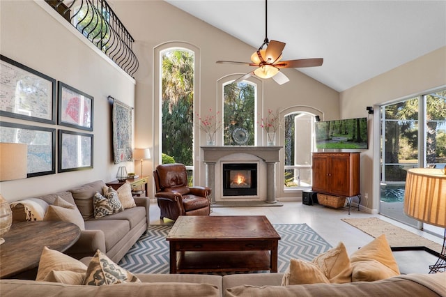 tiled living area featuring a glass covered fireplace, a ceiling fan, and high vaulted ceiling