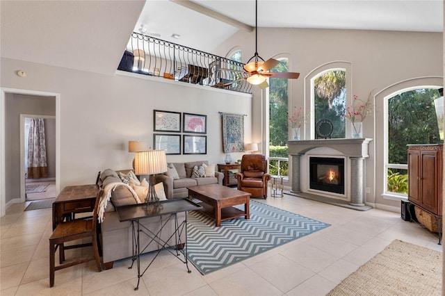 tiled living area with beam ceiling, high vaulted ceiling, a ceiling fan, a glass covered fireplace, and baseboards