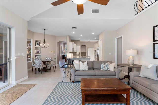 living area with ceiling fan with notable chandelier, recessed lighting, arched walkways, light tile patterned floors, and baseboards