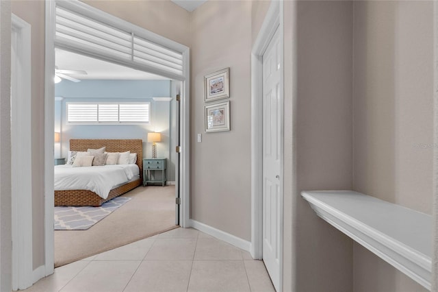 bedroom featuring light tile patterned floors, a closet, baseboards, and light colored carpet