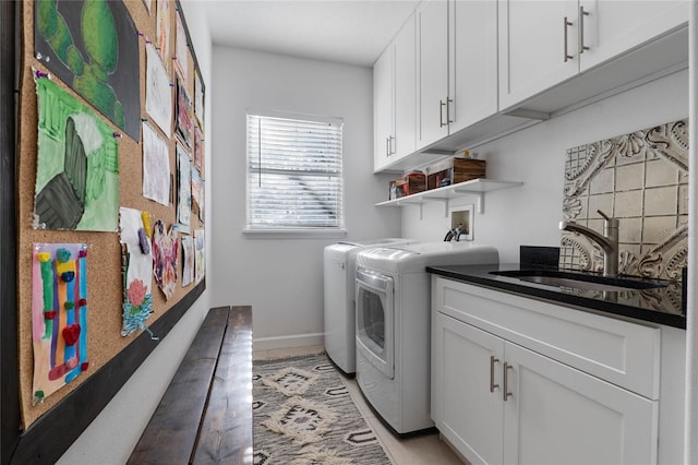 laundry area with cabinet space, independent washer and dryer, baseboards, and a sink