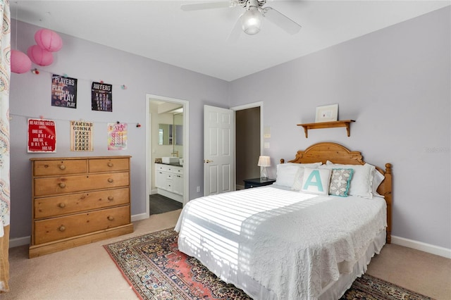 bedroom featuring ensuite bath, light colored carpet, baseboards, and ceiling fan