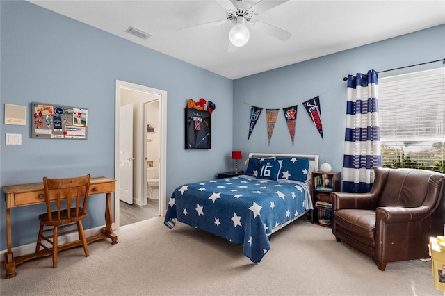 carpeted bedroom with ceiling fan, visible vents, and ensuite bath