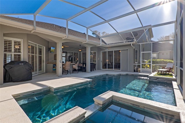 view of swimming pool featuring grilling area, a pool with connected hot tub, ceiling fan, glass enclosure, and a patio area