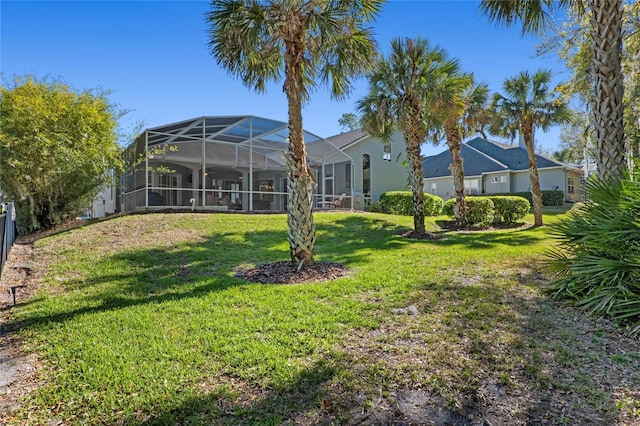 rear view of house featuring a lanai, a lawn, and stucco siding