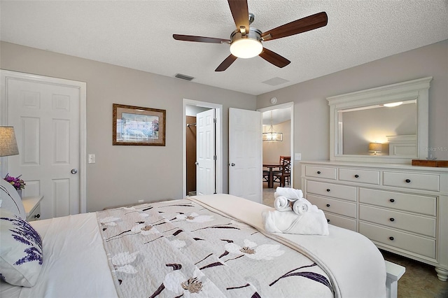 bedroom with visible vents, a textured ceiling, ceiling fan, and dark carpet