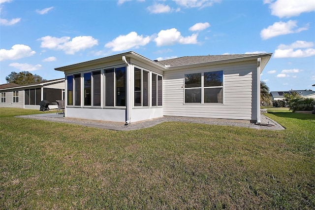rear view of house featuring a yard and a sunroom