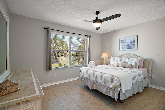 bedroom featuring a textured ceiling, light tile patterned floors, baseboards, and ceiling fan